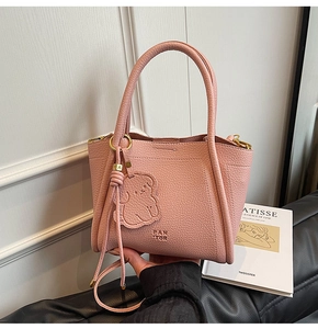 Pink lychee grain leather bucket bag detail with gold hardware and bear charm