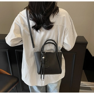 Détail du cuir noir grainé litchi et du logo de marque embossé sur le sac à main