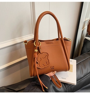 Detail of tan pebble leather bucket bag with gold hardware and dog charm