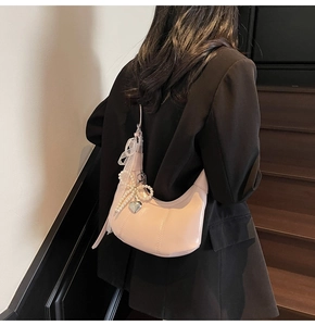 Detail of light pink half-moon shoulder bag with pearl bow and heart charm accent