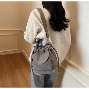 Vue détaillée d'un modèle portant le sac seau en toile gris foncé à cordon coulissant