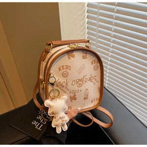 Close-up of litchi grain cream backpack with brown trim and bear doll charm