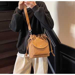 Détail du sac seau en toile beige avec cordon de serrage et large bandoulière tissée