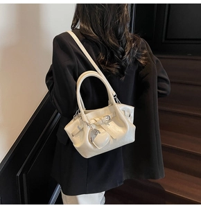 Detalle del bolso tipo cubo blanco crema con textura de cuero granulado y colgante de corazón