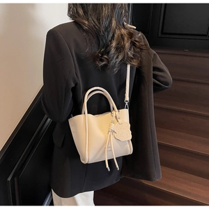 Sac seau en cuir grainé beige orné d'un charm ours et d'un détail de pompon chic
