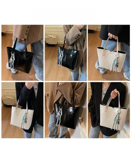 Detail showing high-gloss synthetic leather tote bag with decorative charms and long straps