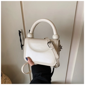 Close-up of a cream-colored mini crossbody bag with a smooth texture and silver hardware