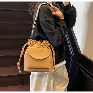 Détail du sac seau en toile beige avec cordon de serrage et bandoulière réglable