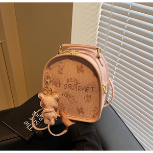Detail showing pink leather backpack with vintage bear pattern and gold metal hardware