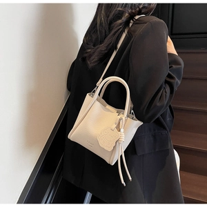 Détail du sac à main blanc cassé en cuir grainé avec pendentif chien et bandoulière