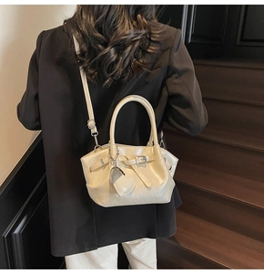 Detalle de bolso bucket blanco crema con colgante de corazón y textura de cuero