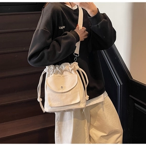 Vue détaillée du sac seau en toile blanche avec cordon de serrage et poche frontale