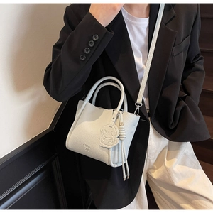 Détail d'un sac à main blanc en cuir grainé avec logo CHAO 2011 et breloque ours