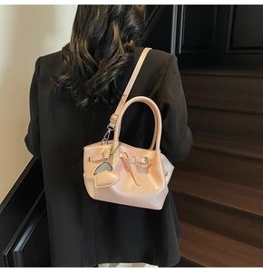 Detalle de bolso tipo cubo rosa brillante con colgante de corazón llevado por modelo