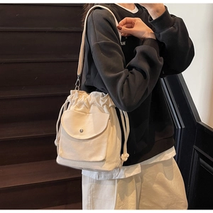 Détail du sac seau en toile blanc cassé avec cordon et bandoulière sur mannequin