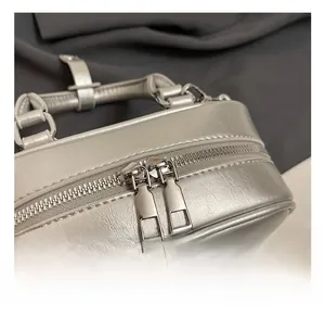 Detail view of silver pillow bag featuring dual metal zippers and fine leather texture