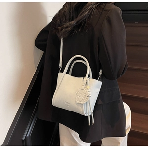 Détail du mini sac cabas en cuir blanc avec bandoulière réglable et breloque de dessin animé