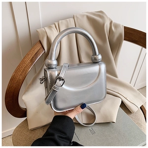 Detailed close-up of metallic silver mini handbag with ball handle and shoulder strap