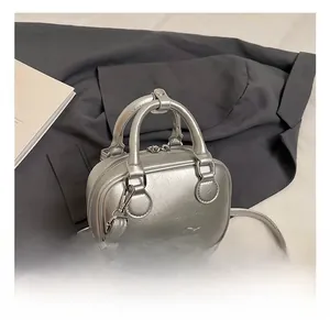 Close-up of retro silver metallic textured handbag with embossed logo on grey suit