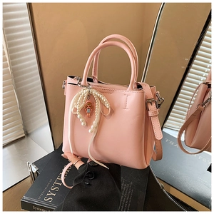 Pink PU leather bucket bag detail showing pearl bow and cute doll charm with adjustable strap