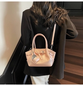 Bolso de hombro rosa con dije de corazón usado por modelo en escalera de madera