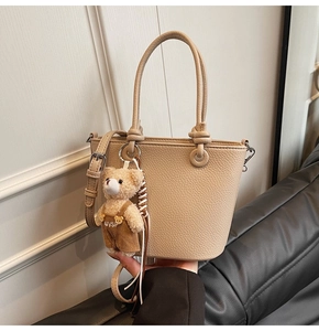 Dettaglio borsa a secchiello beige in pelle martellata con ciondolo a forma di orsetto