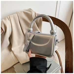 Detail view of mini silver mirror bag with unique knotted handle and metallic finish