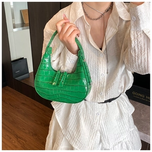 Dettaglio della borsa a mezzaluna verde brillante con trama coccodrillo e doppia zip elegante