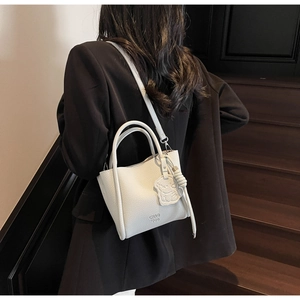 Détail d'un sac à main blanc en cuir grainé avec logo CHAO 1509 et breloque mignonne