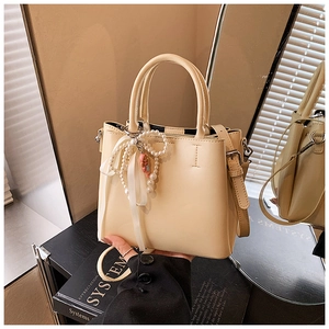 Detail of cream bucket bag with pearl ribbon charm and polished silver hardware