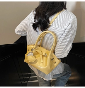 Detalle de bolso cubo amarillo brillante con colgante de corazón y bandolera