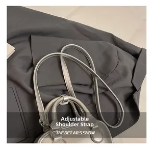 Detailed view of metallic silver pillow bag with adjustable shoulder strap and leather texture