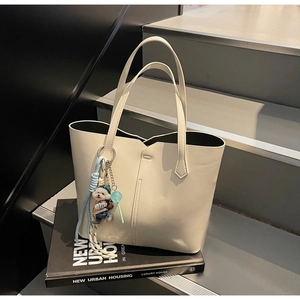 Detail of cream PU leather tote bag with cute bear charm on interior design books