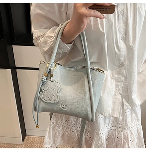 Close-up of light blue leather tote bag with PAN TOR logo and cute dog-shaped charm