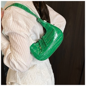 Dettaglio della trama a coccodrillo verde brillante su borsa a tracolla a mezzaluna argentata