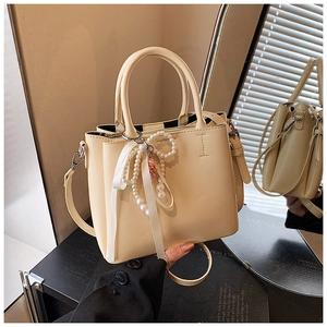 Detailed view of cream-colored PU leather bucket bag with pearl bow and ribbon accents