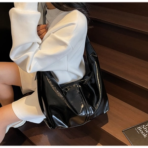 Detail of glossy black large tote bag showing high-shine texture and crescent shape
