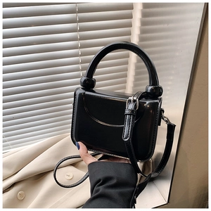 Detail view of black glossy PU leather square bag with unique circular handle grip