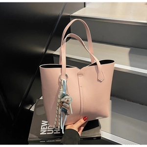 Detail of pink faux leather tote bag featuring a cute puppy charm on gray stairs