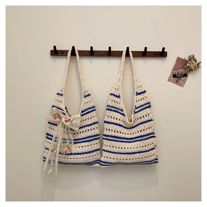 Détail de sacs fourre-tout tricotés avec rayures bleues et décoration nœud floral en dentelle
