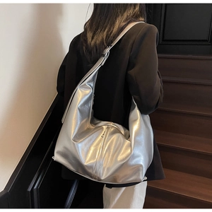 Detail view of large silver metallic tote bag shown on model for shoulder wear