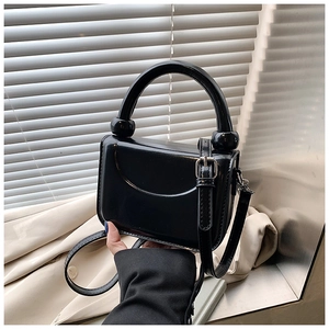 Detail of black glossy leather handbag with unique circular handle and silver hardware