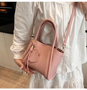 Pink lychee grain leather mini bucket bag with PAN TOR logo and animal charm