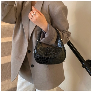 Dettaglio della borsa a mezzaluna in vernice nera con texture coccodrillo impressa