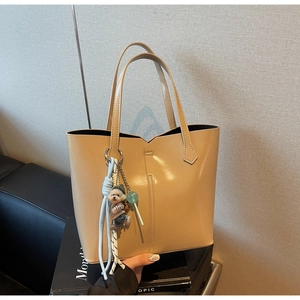 Detail of light khaki tote bag featuring a cute puppy charm and refined vertical stitching