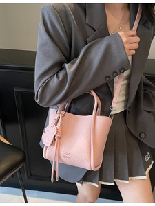 Petit sac à main rose motif litchi avec bandoulière réglable porté par un mannequin