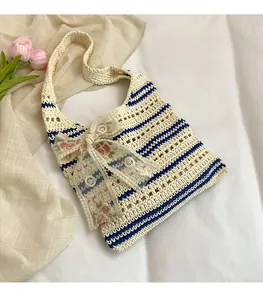 Détail d'un cabas tissé avec rayures bleues et nœud en dentelle rose florale