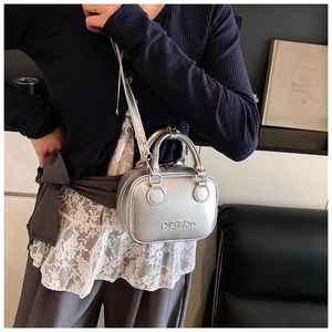 Detail of silver metallic mini bowling bag featuring retro embossed text and slim shoulder strap