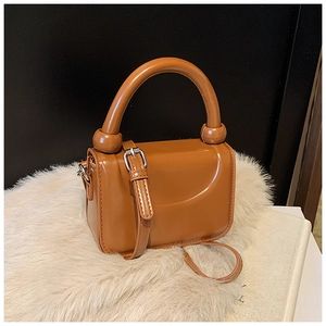 Detailed close-up of brown mini square bag with silver buckle on white plush surface