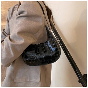 Dettaglio ravvicinato della texture a coccodrillo lucida sulla borsa hobo nera